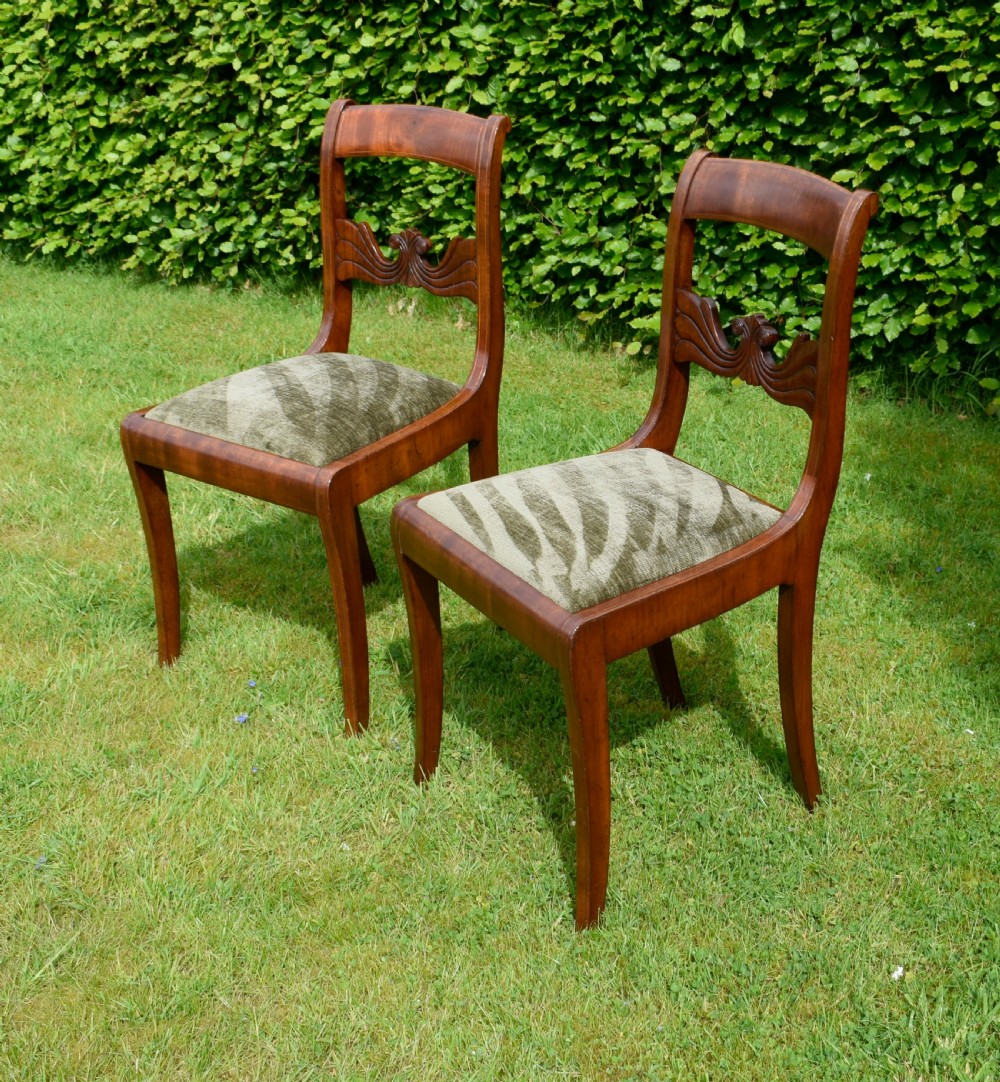A pair of mahogany side chairs with curved tablet top rails, carved back splats, and green patterned upholstered seats.