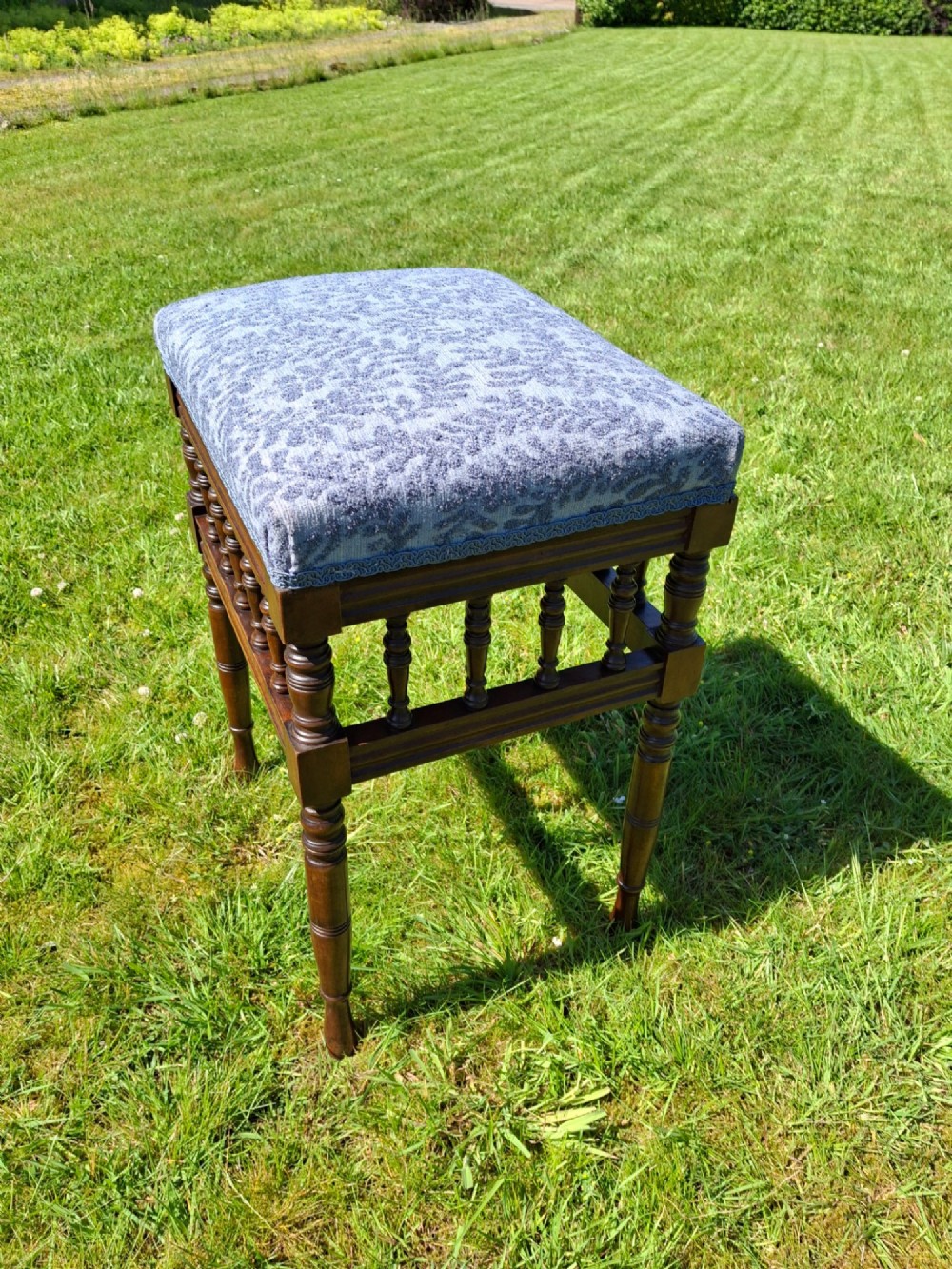 An Edwardian dark wood piano stool with turned spindles and a patterned blue fabric upholstered seat. View III