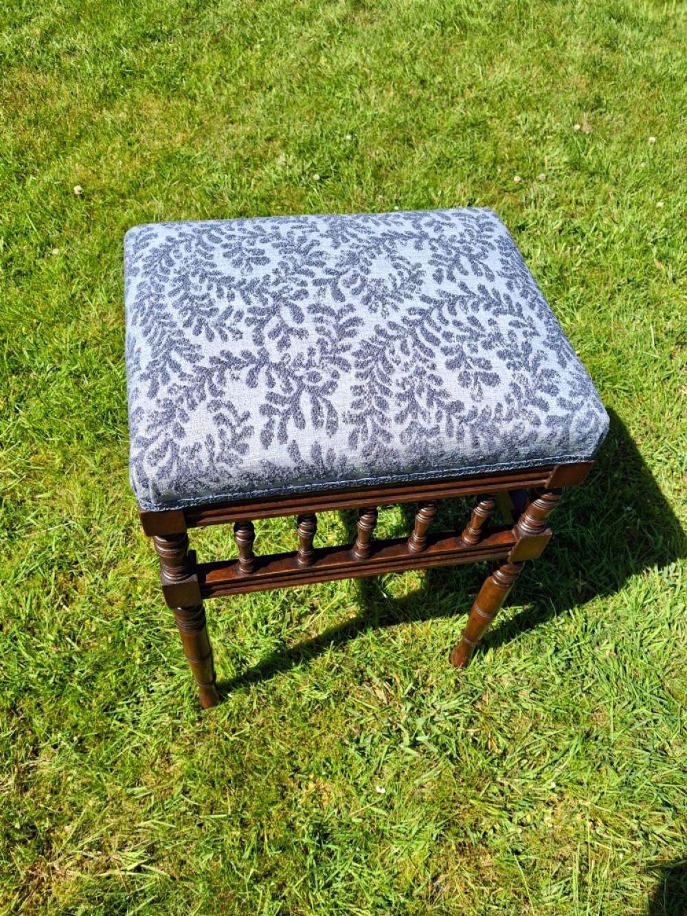An Edwardian dark wood piano stool with turned spindles and a patterned blue fabric upholstered seat. View IV