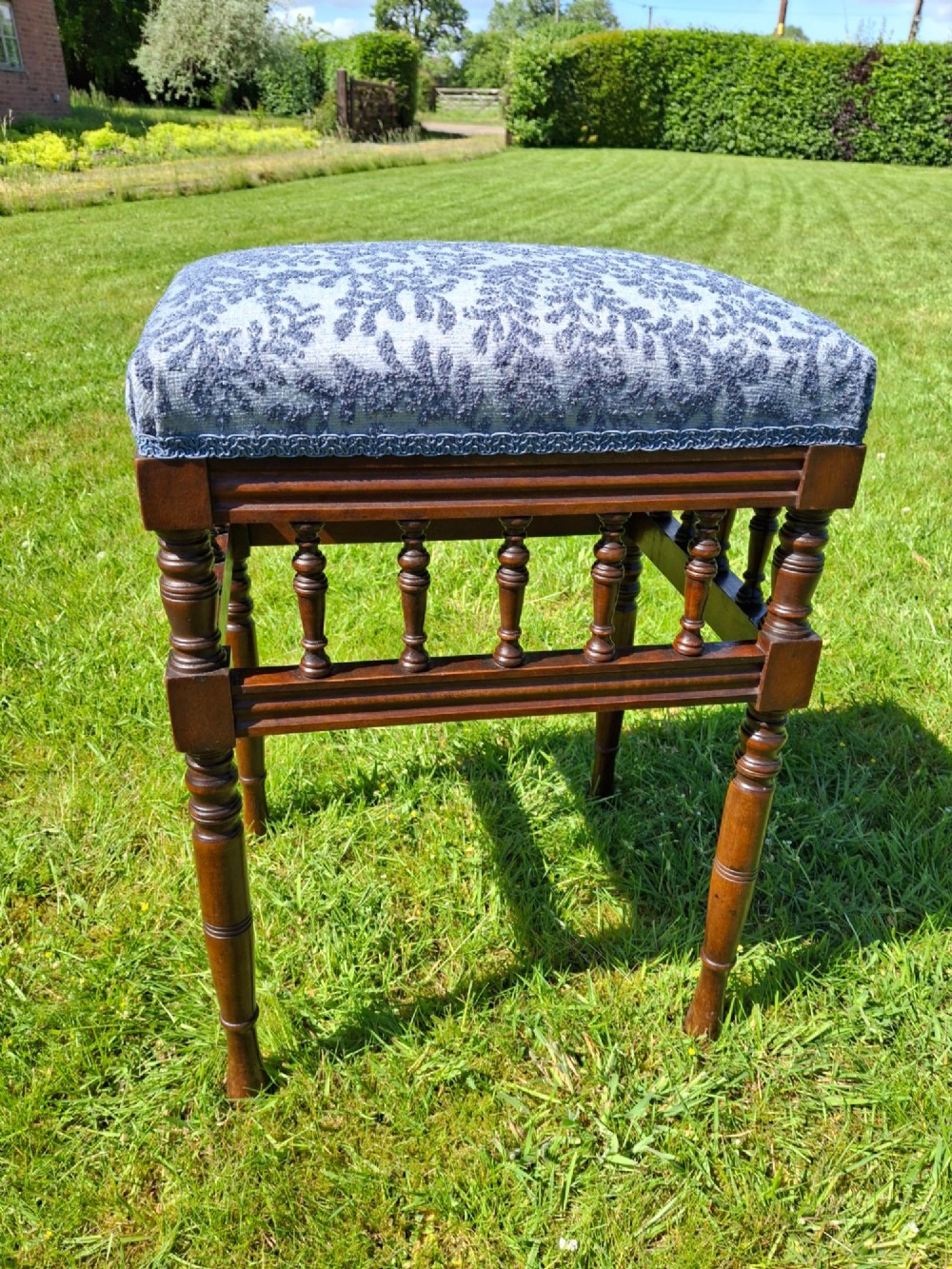An Edwardian dark wood piano stool with turned spindles and a patterned blue fabric upholstered seat. View V
