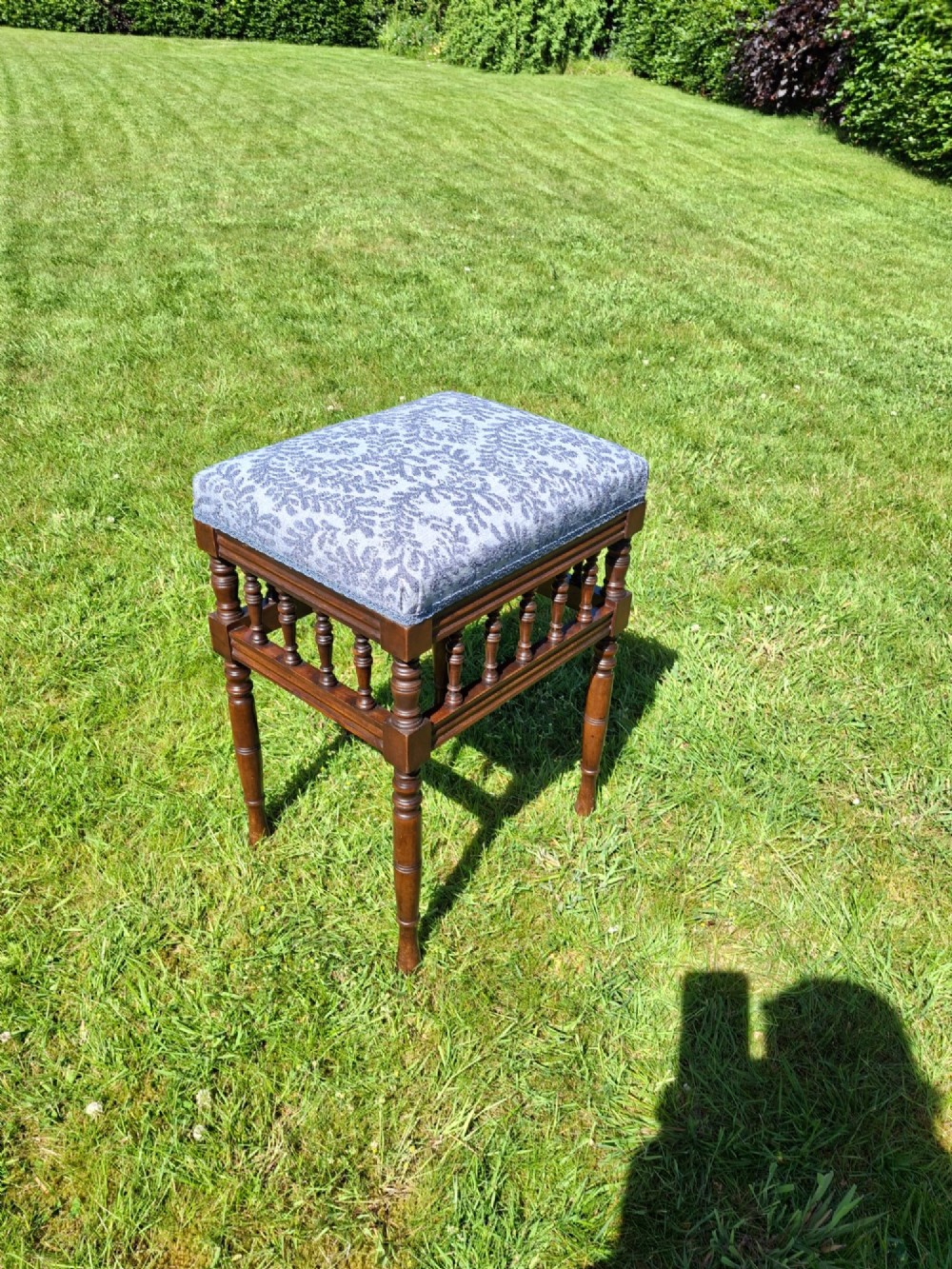 An Edwardian dark wood piano stool with turned spindles and a patterned blue fabric upholstered seat. View VI