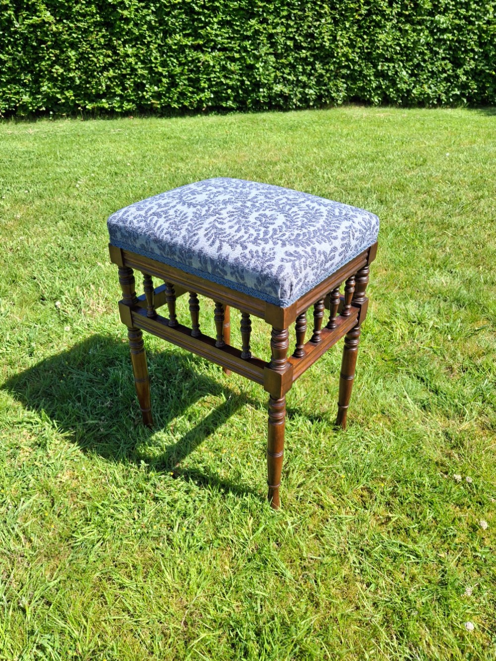 An Edwardian dark wood piano stool with turned spindles and a patterned blue fabric upholstered seat. View VIII