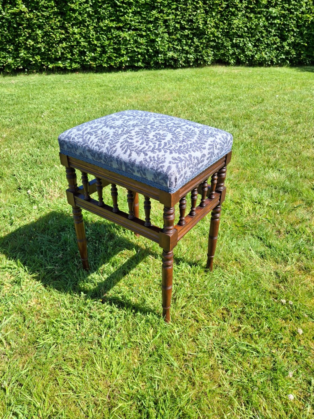 An Edwardian dark wood piano stool with turned spindles and a patterned blue fabric upholstered seat. View IX