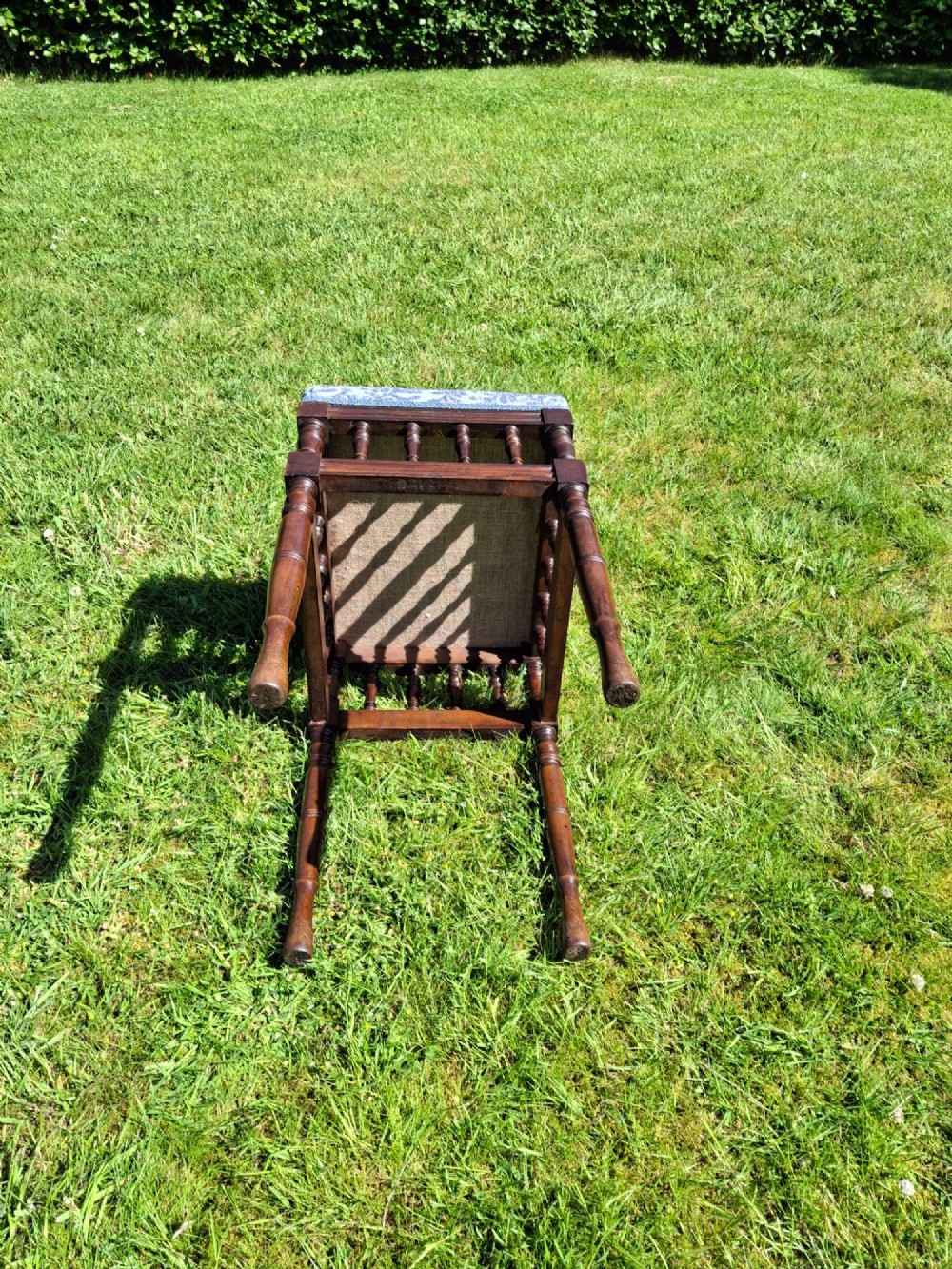 An Edwardian dark wood piano stool with turned spindles and a patterned blue fabric upholstered seat. View X