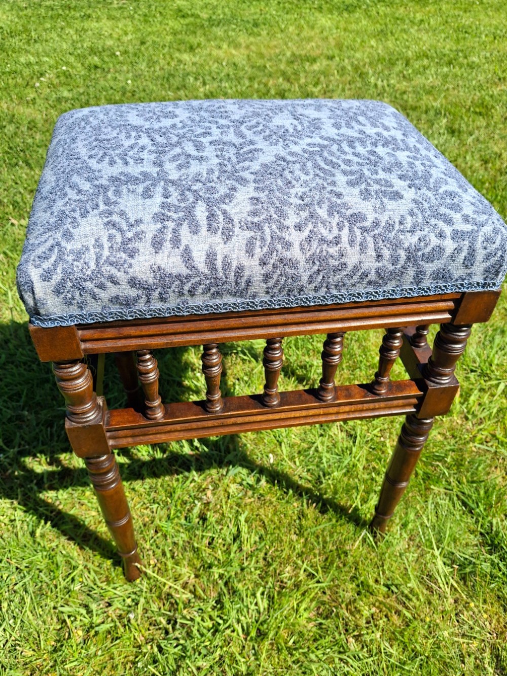 An Edwardian dark wood piano stool with turned spindles and a patterned blue fabric upholstered seat. View XI
