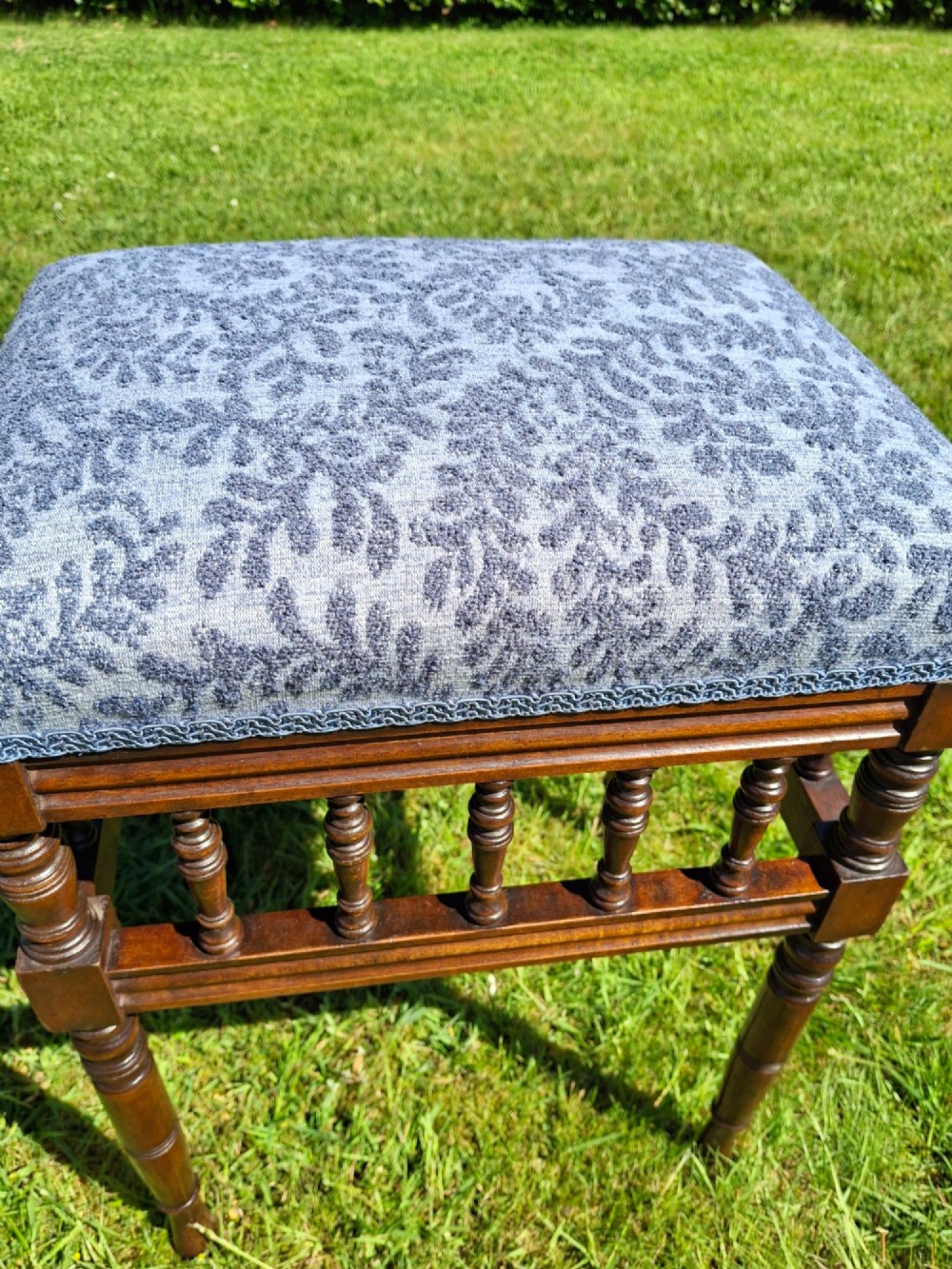 An Edwardian dark wood piano stool with turned spindles and a patterned blue fabric upholstered seat. View XII