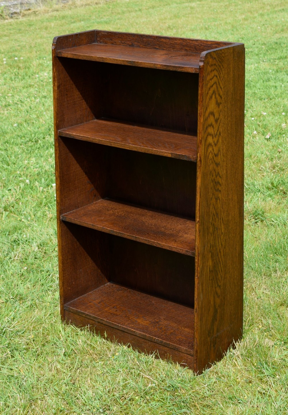 An early 20th-century open oak bookcase featuring four fixed shelves, solid side panels, and a low gallery back top. View II