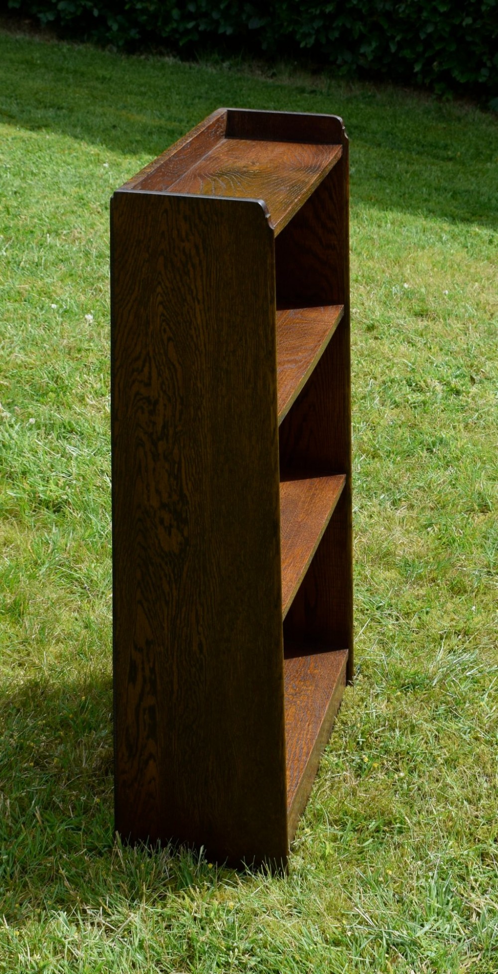 An early 20th-century open oak bookcase featuring four fixed shelves, solid side panels, and a low gallery back top. View IV