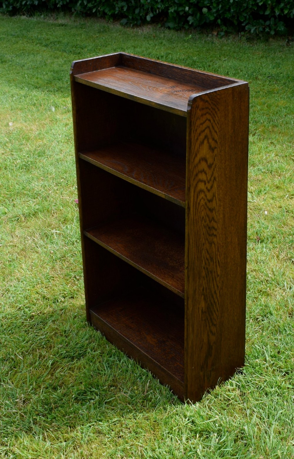 An early 20th-century open oak bookcase featuring four fixed shelves, solid side panels, and a low gallery back top. View VIII