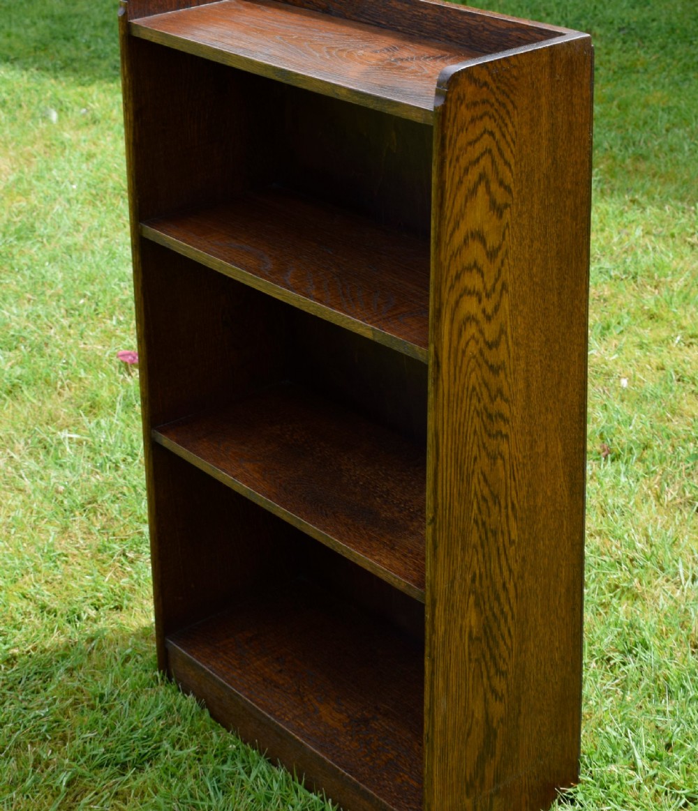 An early 20th-century open oak bookcase featuring four fixed shelves, solid side panels, and a low gallery back top. View IX