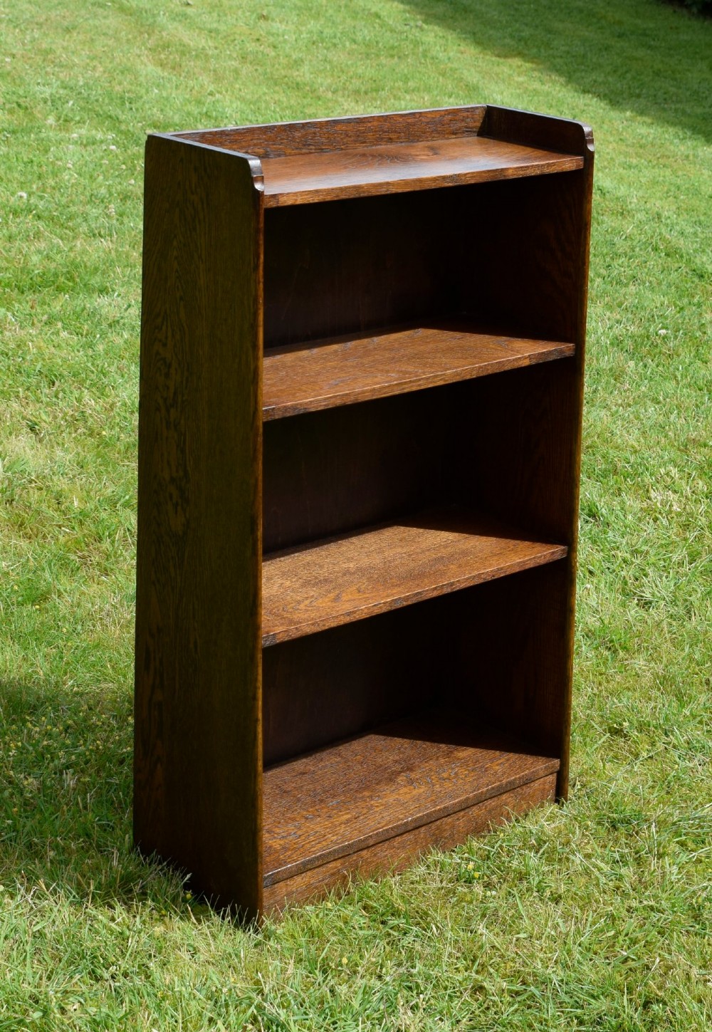 An early 20th-century open oak bookcase featuring four fixed shelves, solid side panels, and a low gallery back top. View XI