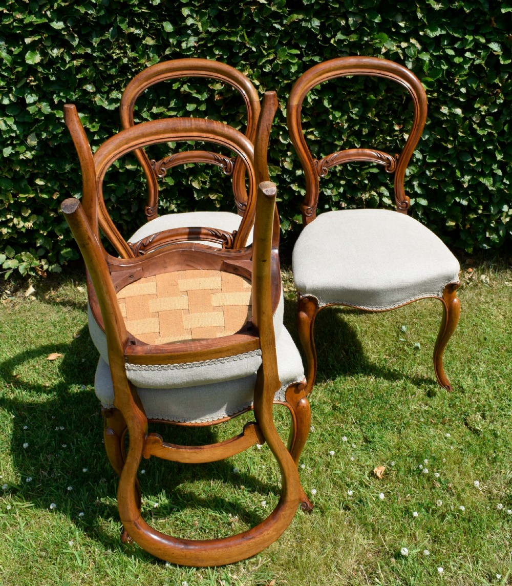 A set of four Victorian walnut balloon-back dining chairs with carved mid-rails, neutral upholstered seats, and cabriole front legs. View IX