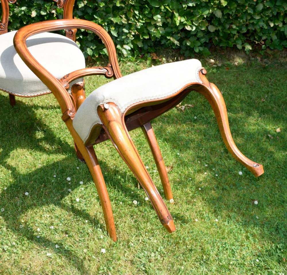 A set of four Victorian walnut balloon-back dining chairs with carved mid-rails, neutral upholstered seats, and cabriole front legs. View XI
