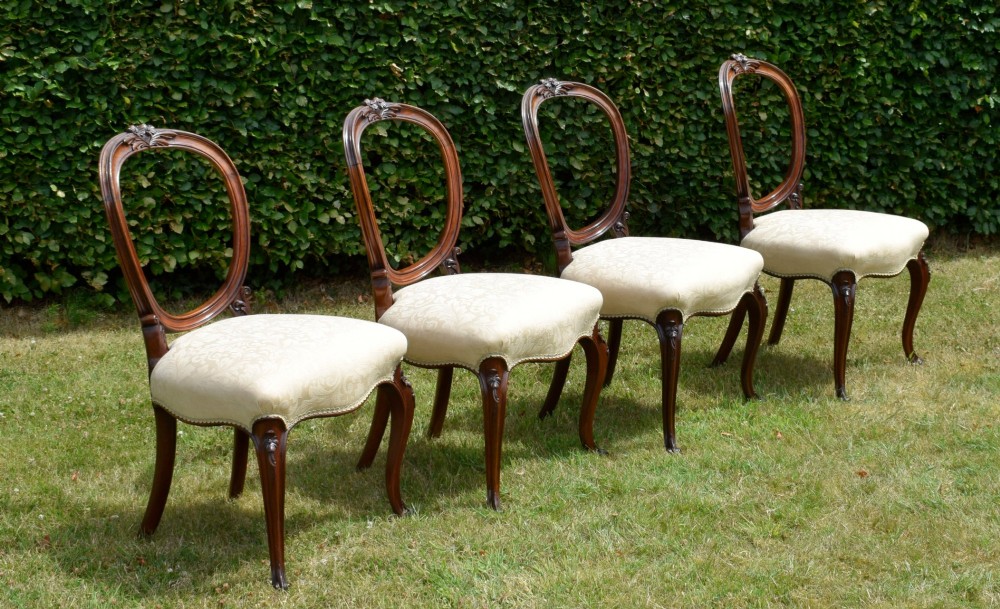A set of four Victorian walnut dining chairs featuring carved balloon backs, cream upholstered seats, and curved cabriole legs. View III