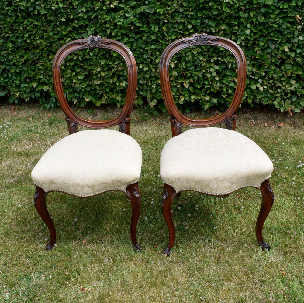 A set of four Victorian walnut dining chairs featuring carved balloon backs, cream upholstered seats, and curved cabriole legs. View IX