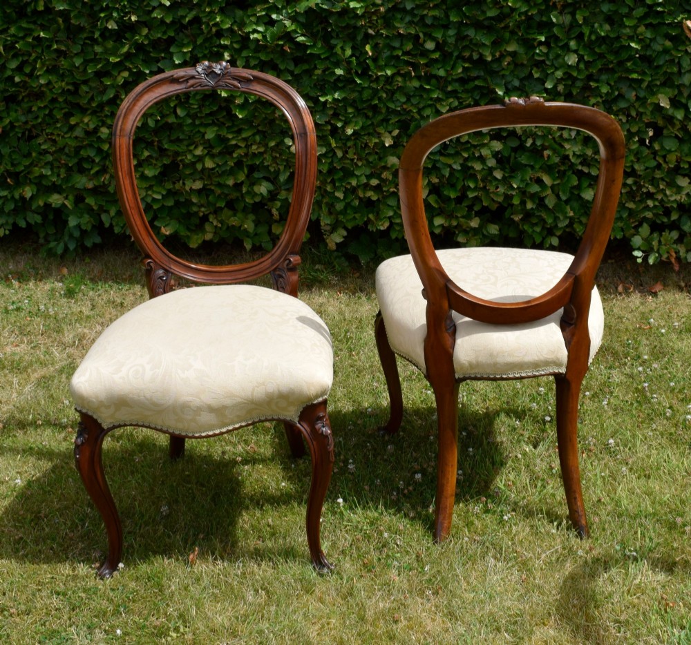 A set of four Victorian walnut dining chairs featuring carved balloon backs, cream upholstered seats, and curved cabriole legs. View XI