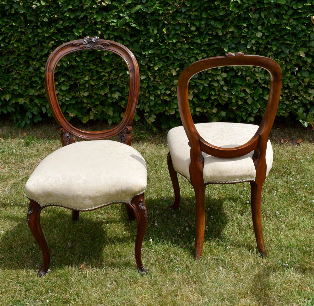 A set of four Victorian walnut dining chairs featuring carved balloon backs, cream upholstered seats, and curved cabriole legs. View XII