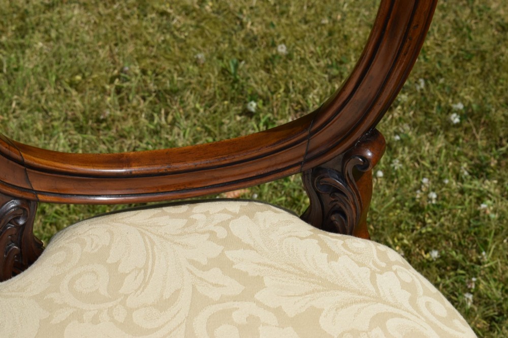 A set of four Victorian walnut dining chairs featuring carved balloon backs, cream upholstered seats, and curved cabriole legs. View XIII