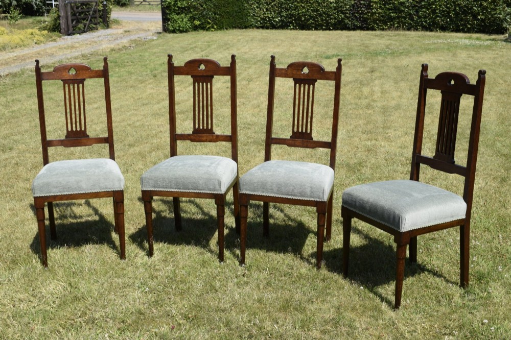 A set of four dark oak Arts and Crafts dining chairs with heart cutouts on the backrests and light grey upholstered seats. View II