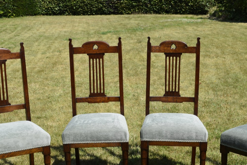A set of four dark oak Arts and Crafts dining chairs with heart cutouts on the backrests and light grey upholstered seats. View III