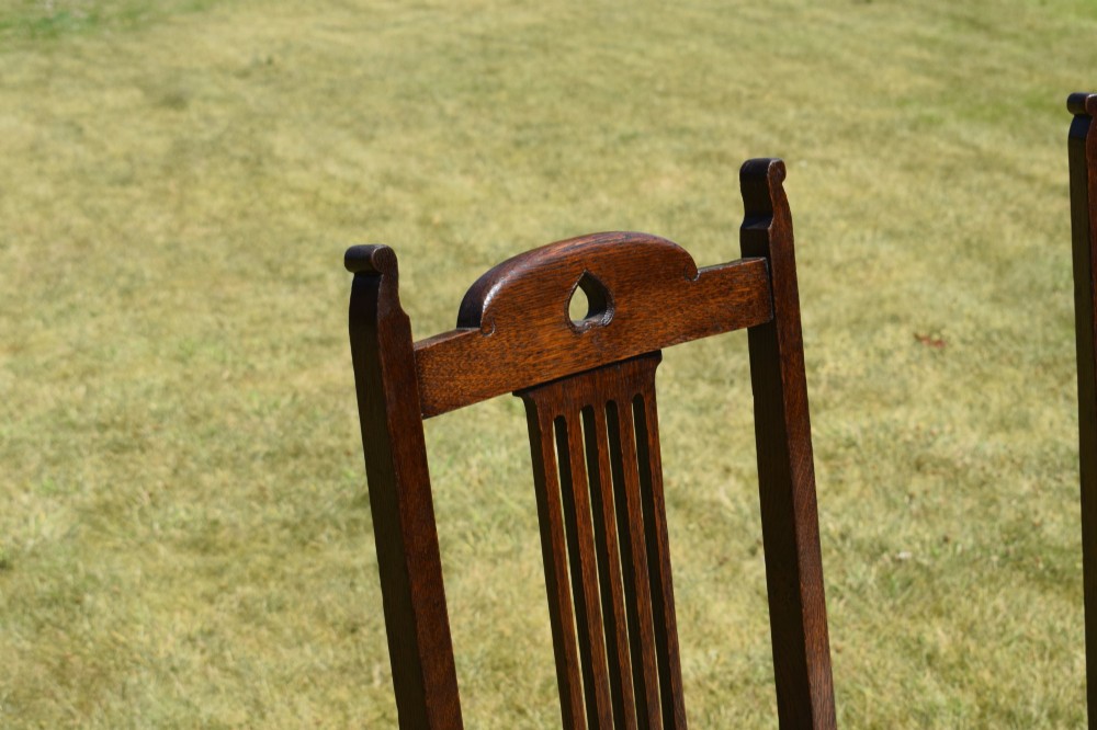 A set of four dark oak Arts and Crafts dining chairs with heart cutouts on the backrests and light grey upholstered seats. View V