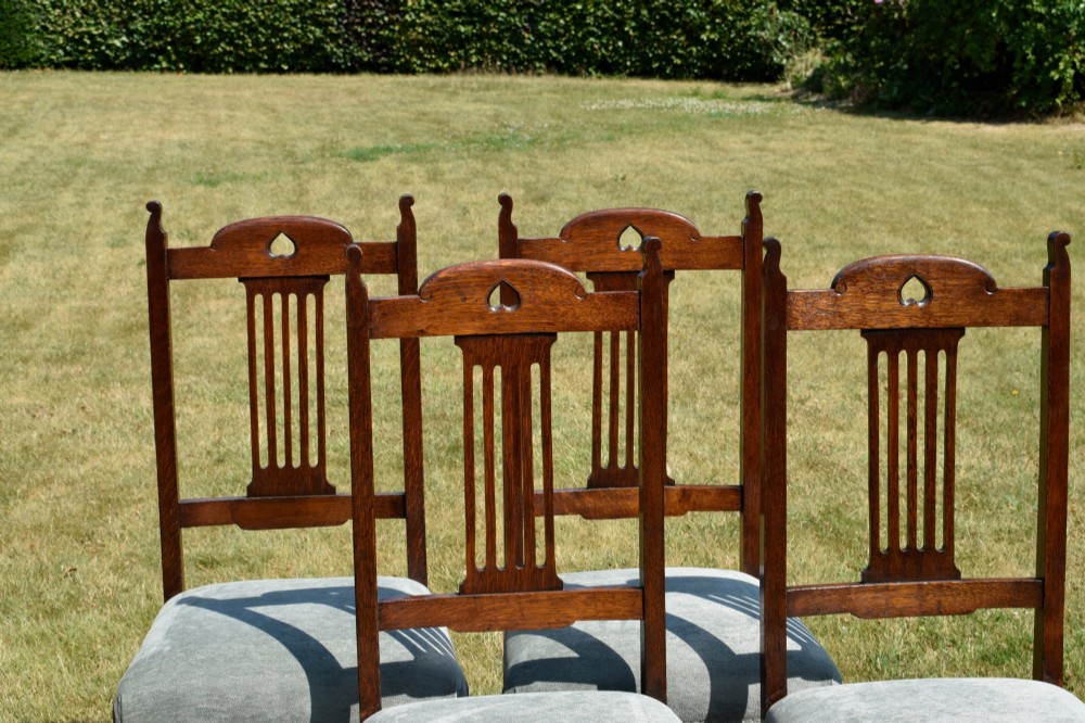 A set of four dark oak Arts and Crafts dining chairs with heart cutouts on the backrests and light grey upholstered seats. View VII