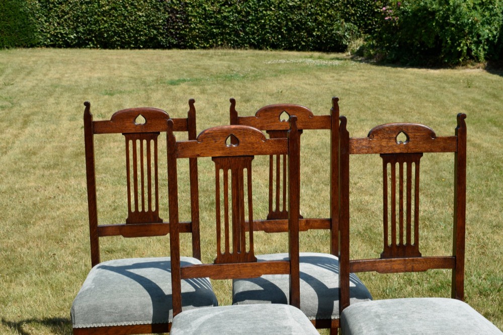 A set of four dark oak Arts and Crafts dining chairs with heart cutouts on the backrests and light grey upholstered seats. View VIII