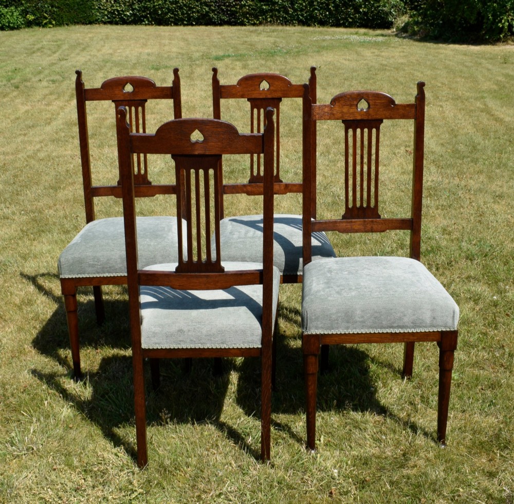 A set of four dark oak Arts and Crafts dining chairs with heart cutouts on the backrests and light grey upholstered seats. View XI