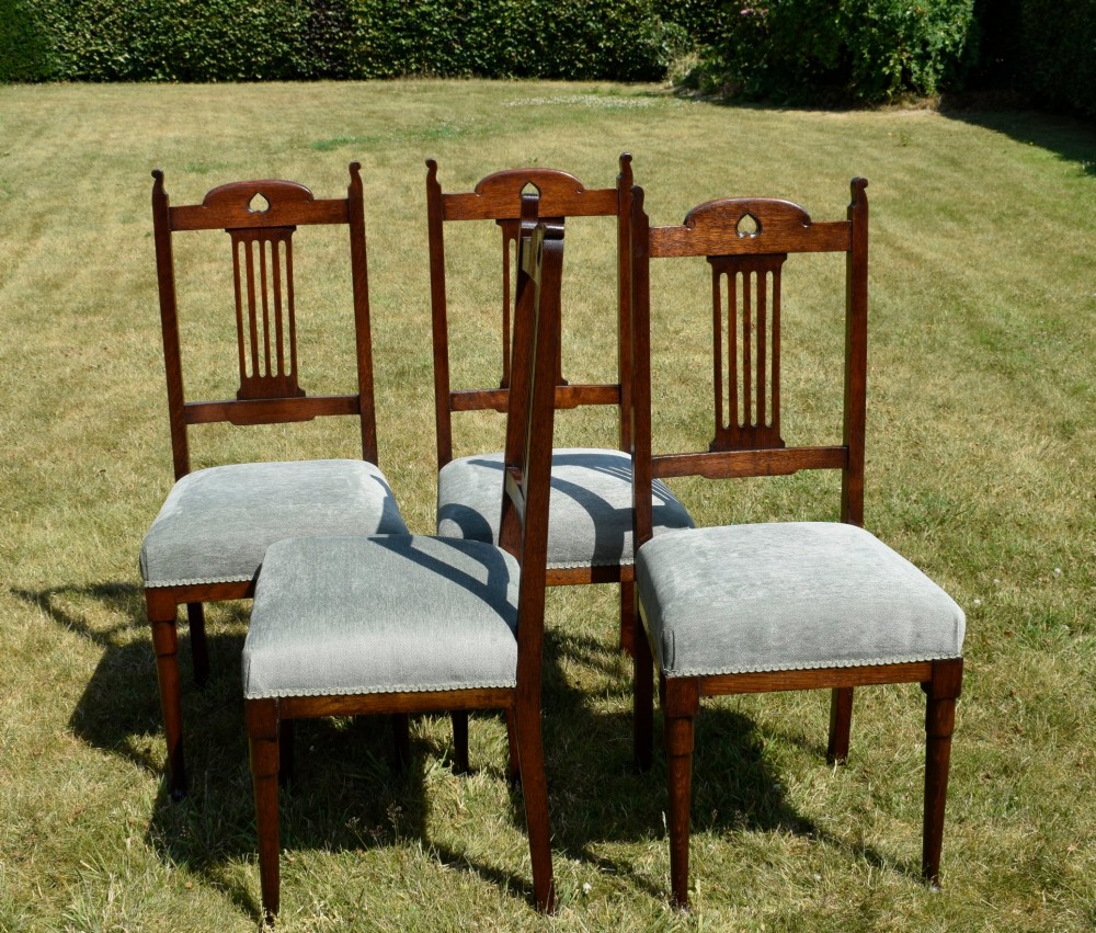 A set of four dark oak Arts and Crafts dining chairs with heart cutouts on the backrests and light grey upholstered seats. View XII