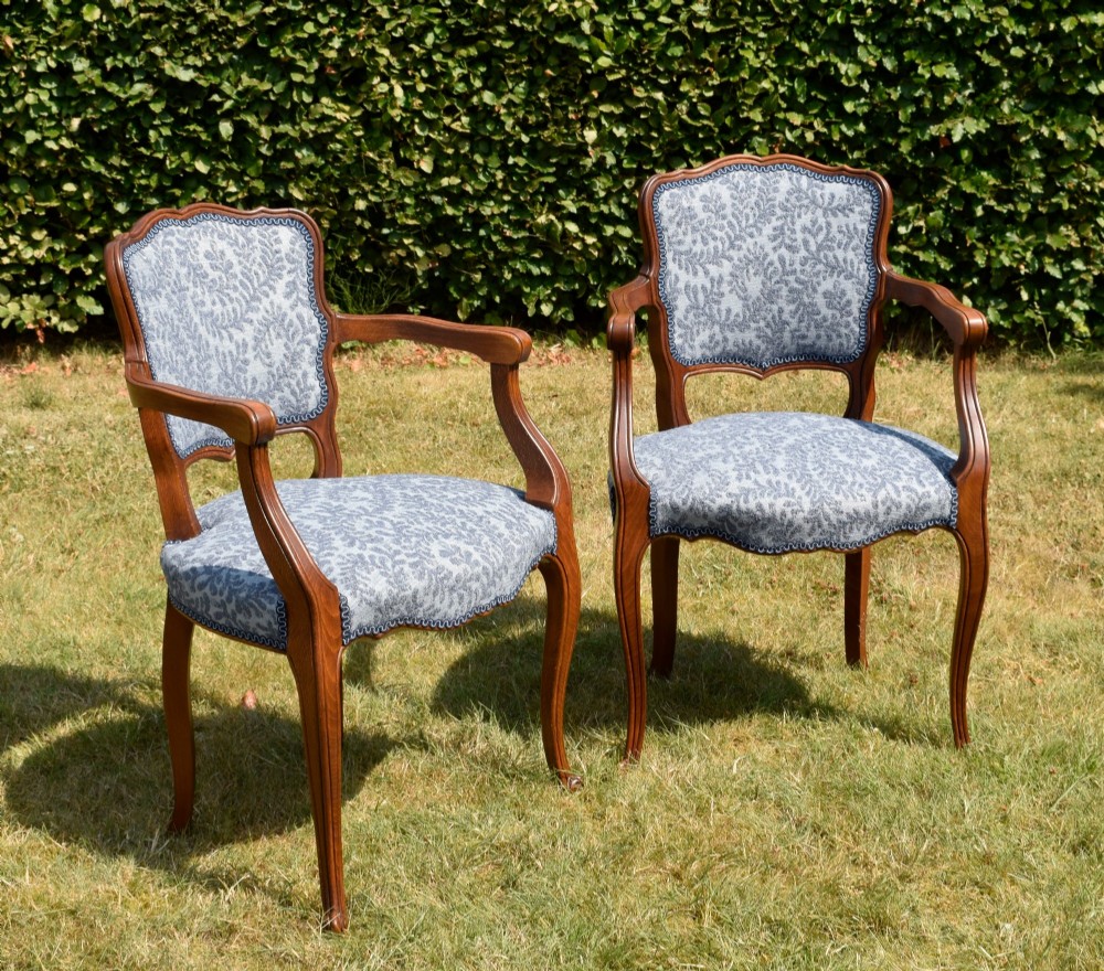 A pair of early 20th-century French armchairs with carved walnut frames, cabriole legs, swept arms, and blue leaf-patterned fabric upholstery. View III
