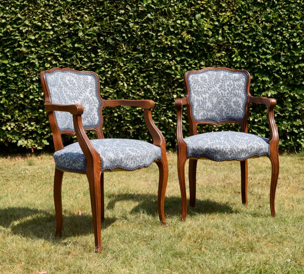 A pair of early 20th-century French armchairs with carved walnut frames, cabriole legs, swept arms, and blue leaf-patterned fabric upholstery. View IV