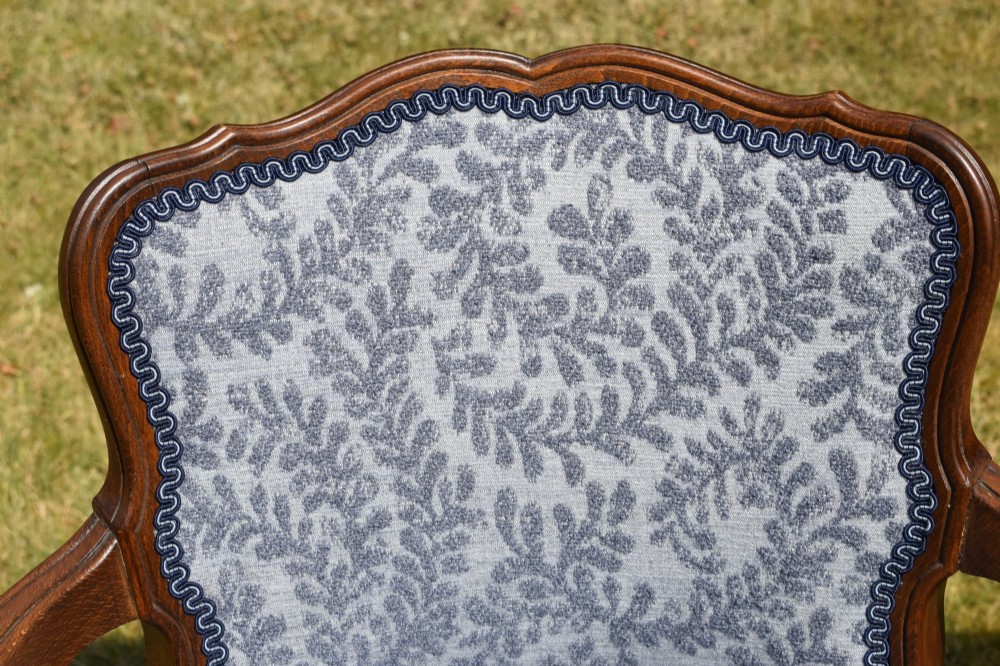 A pair of early 20th-century French armchairs with carved walnut frames, cabriole legs, swept arms, and blue leaf-patterned fabric upholstery. View VII