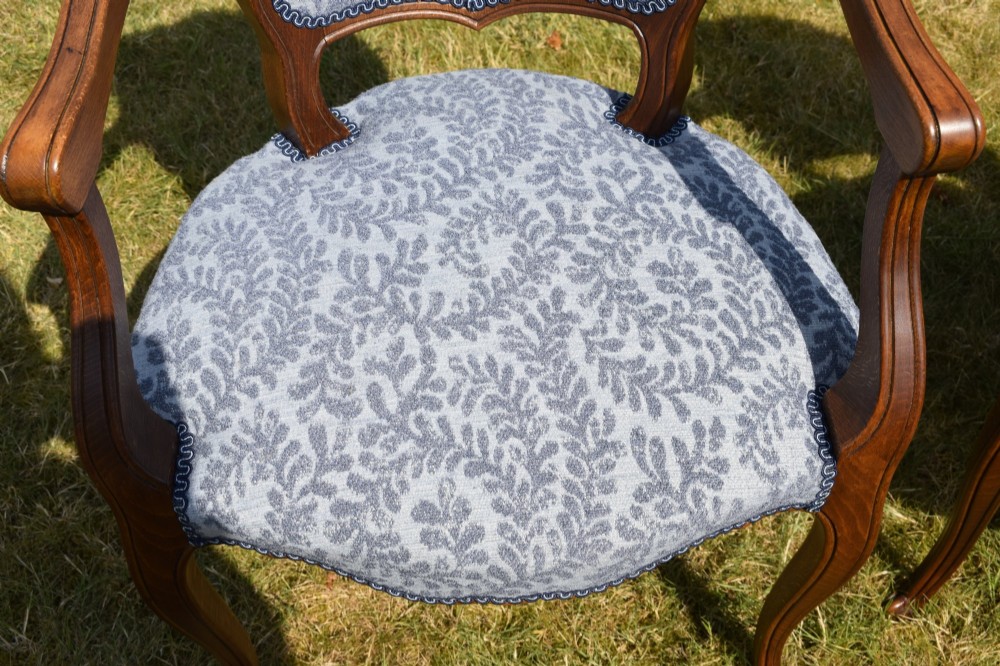 A pair of early 20th-century French armchairs with carved walnut frames, cabriole legs, swept arms, and blue leaf-patterned fabric upholstery. View VIII