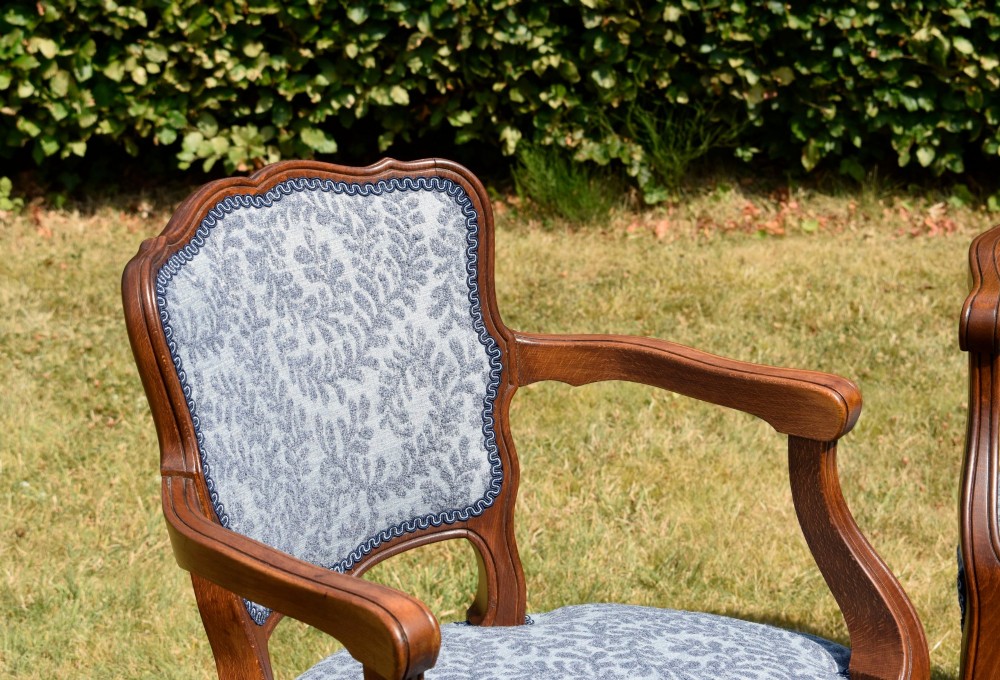 A pair of early 20th-century French armchairs with carved walnut frames, cabriole legs, swept arms, and blue leaf-patterned fabric upholstery. View XI