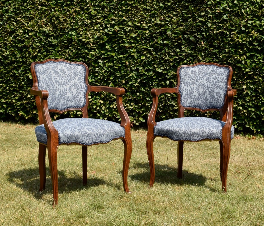 A pair of early 20th-century French armchairs with carved walnut frames, cabriole legs, swept arms, and blue leaf-patterned fabric upholstery. View XII