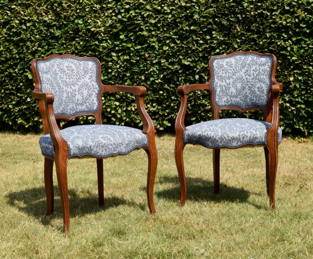 A pair of early 20th-century French armchairs with carved walnut frames, cabriole legs, swept arms, and blue leaf-patterned fabric upholstery. View XIII
