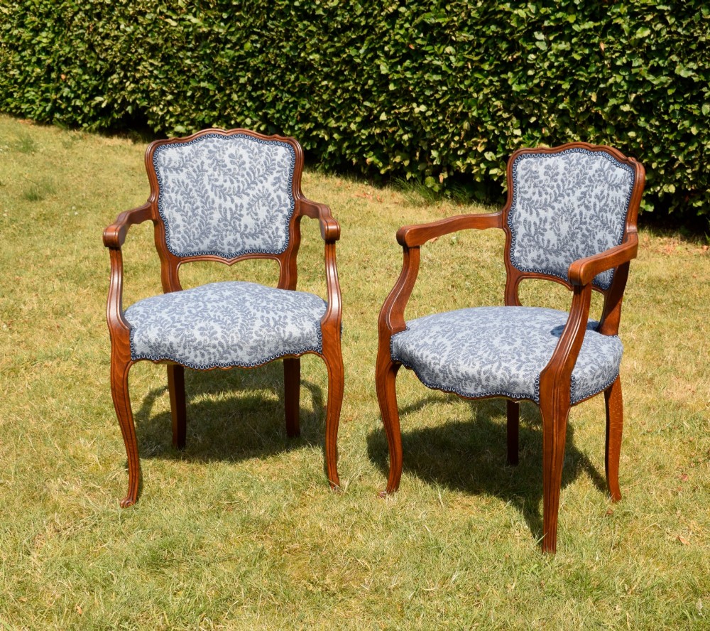 A pair of early 20th-century French armchairs with carved walnut frames, cabriole legs, swept arms, and blue leaf-patterned fabric upholstery. View XV