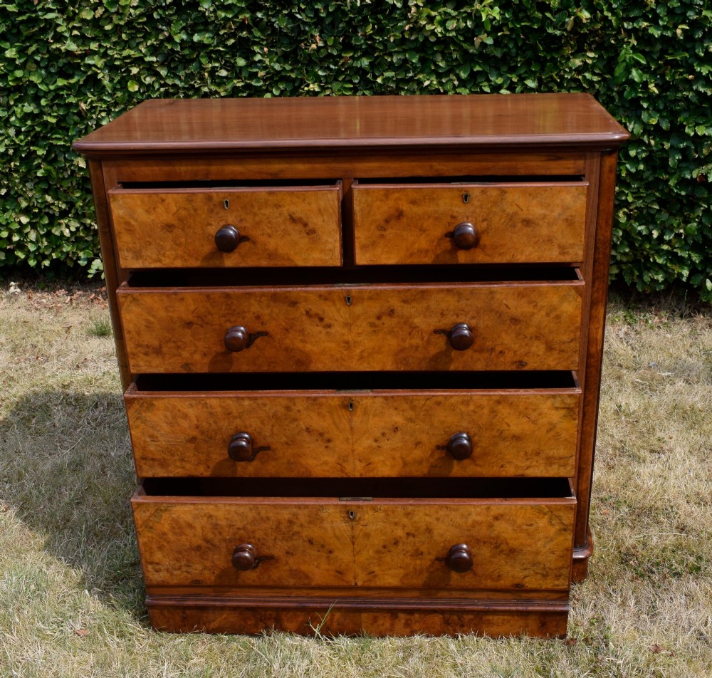 A Victorian burr walnut chest of drawers featuring two short over three long graduated drawers with turned wooden knobs and a solid plinth base. View VII