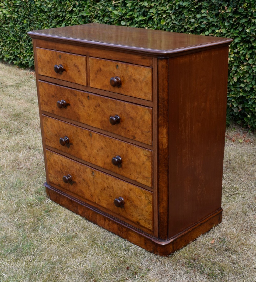 A Victorian burr walnut chest of drawers featuring two short over three long graduated drawers with turned wooden knobs and a solid plinth base. View IX