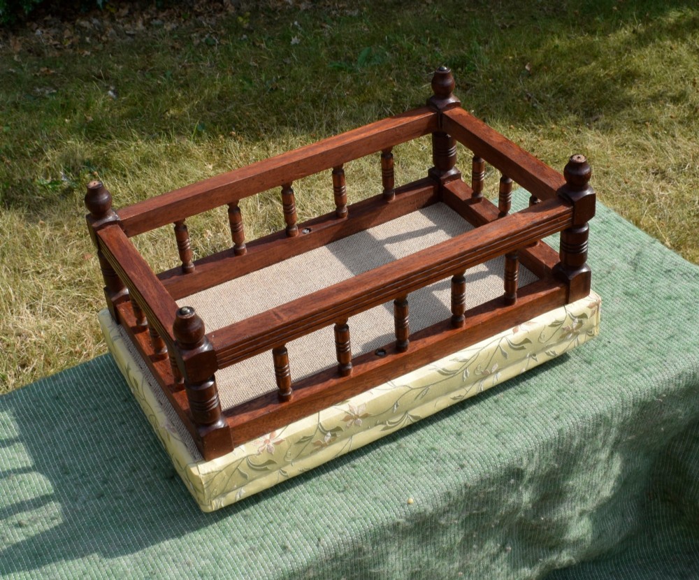 A low rectangular mahogany footstool featuring turned wood spindles and a yellow floral pattern padded fabric top. View VI