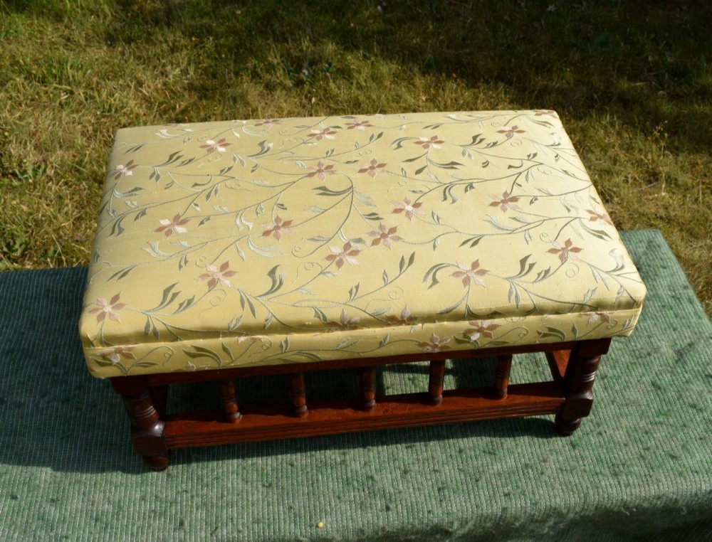 A low rectangular mahogany footstool featuring turned wood spindles and a yellow floral pattern padded fabric top. View VIII