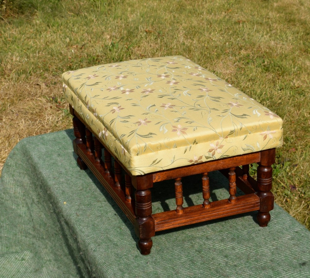 A low rectangular mahogany footstool featuring turned wood spindles and a yellow floral pattern padded fabric top. View IX