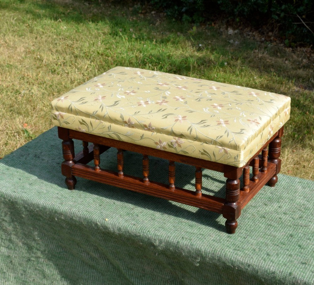 A low rectangular mahogany footstool featuring turned wood spindles and a yellow floral pattern padded fabric top. View XII