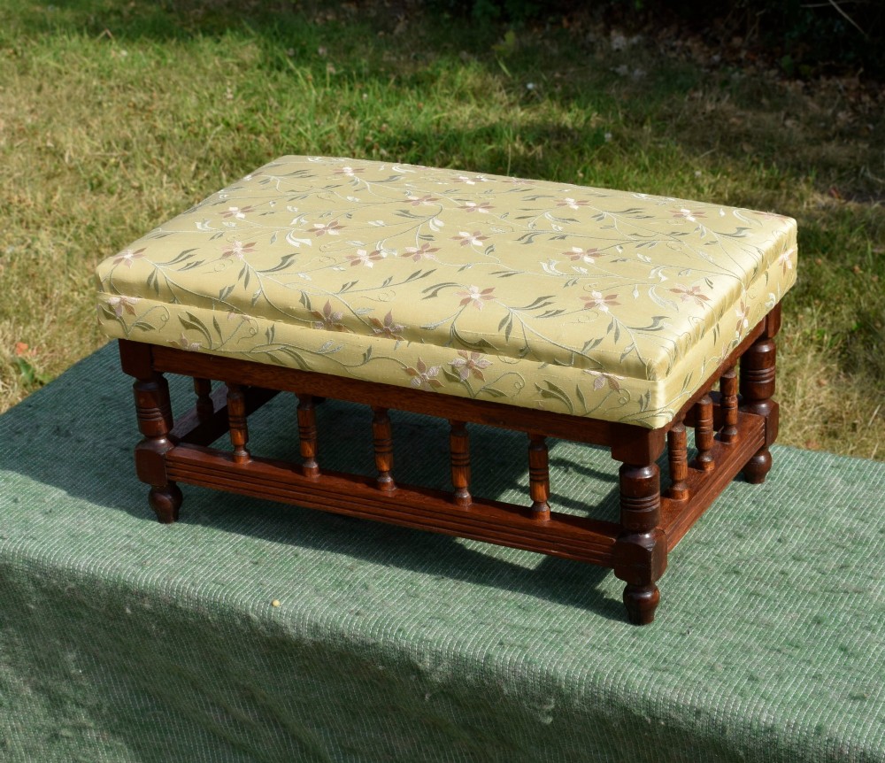 A low rectangular mahogany footstool featuring turned wood spindles and a yellow floral pattern padded fabric top. View XIII