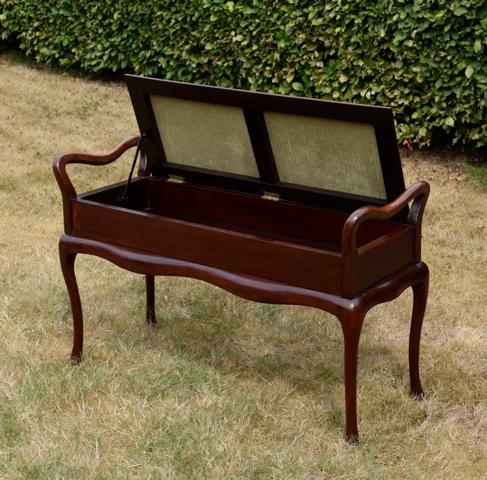 A mahogany duet piano stool with a blue patterned upholstered seat and carved cabriole legs. View X
