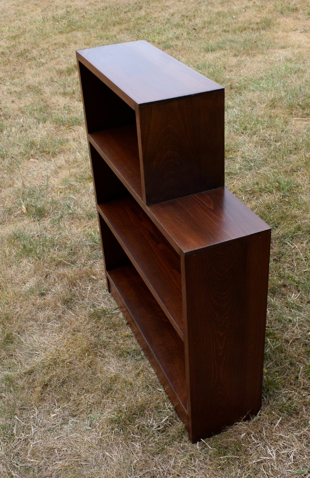A dark brown wooden Art Deco bookcase featuring an asymmetrical stepped design with three open shelves. View VII
