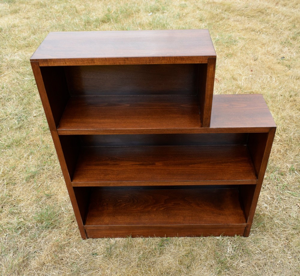 A dark brown wooden Art Deco bookcase featuring an asymmetrical stepped design with three open shelves. View IX