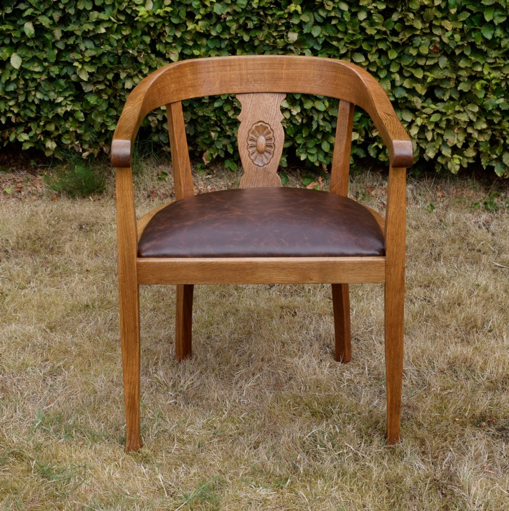 An early 20th-century oak desk chair featuring a curved horseshoe backrest, a carved central splat, and a dark brown upholstered seat pad. View II