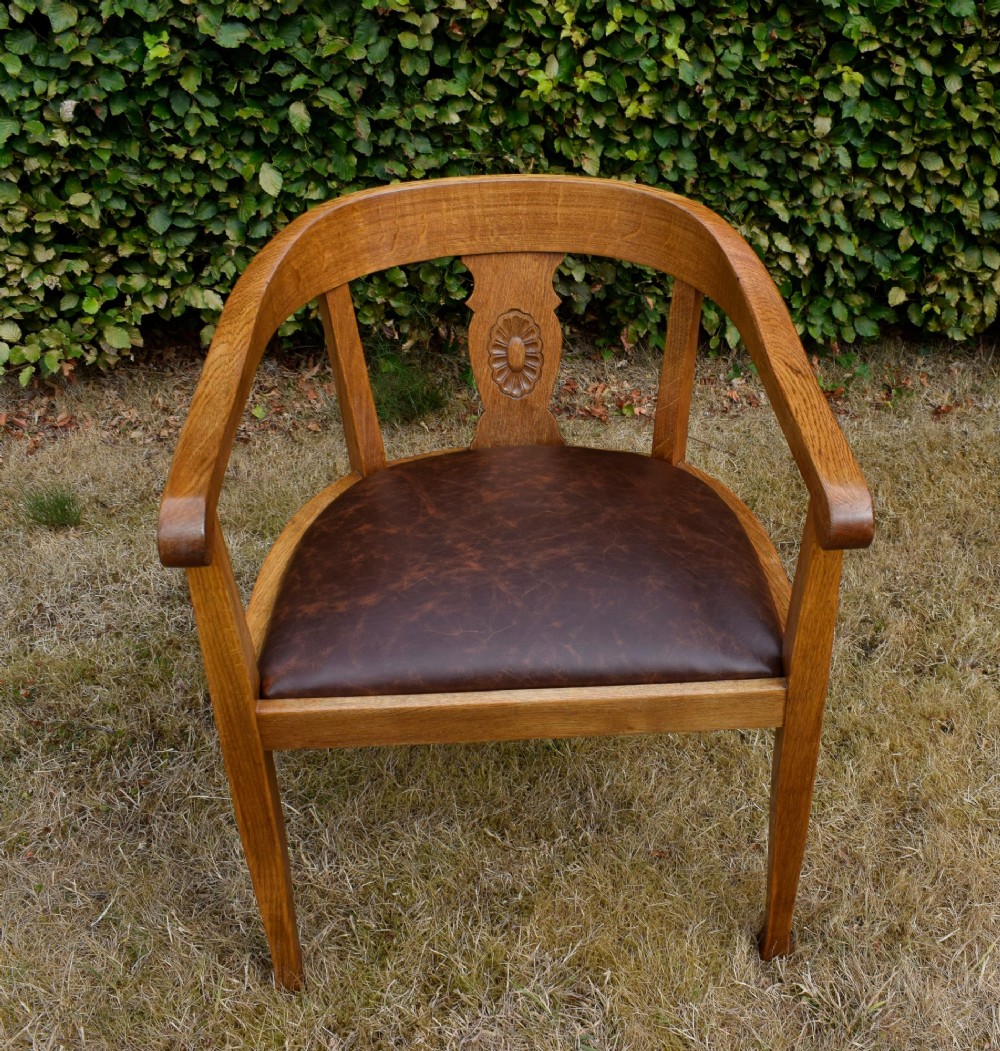 An early 20th-century oak desk chair featuring a curved horseshoe backrest, a carved central splat, and a dark brown upholstered seat pad. View XIII