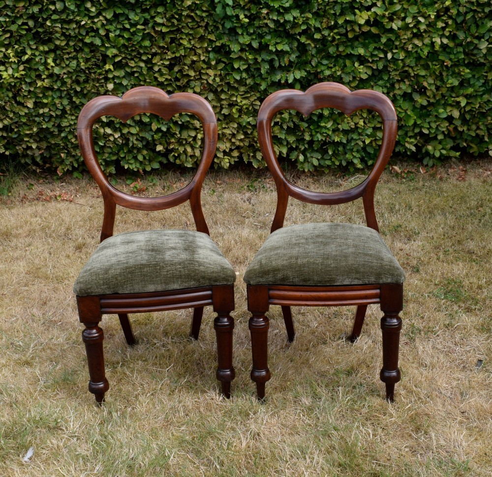 A pair of Victorian mahogany crown back dining chairs with green velvet upholstered seats and turned front legs. View X
